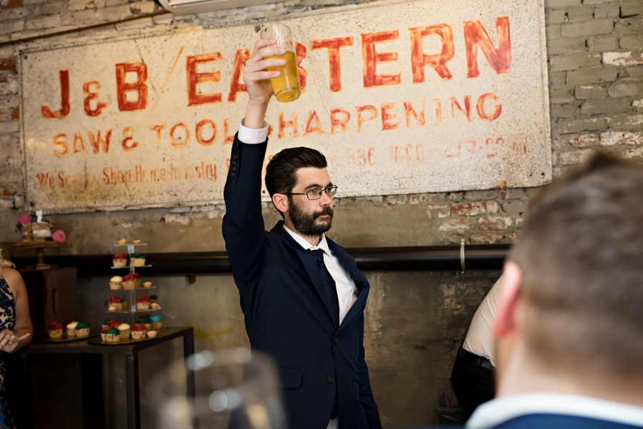 The best man toasting his beer to the bride and groom.